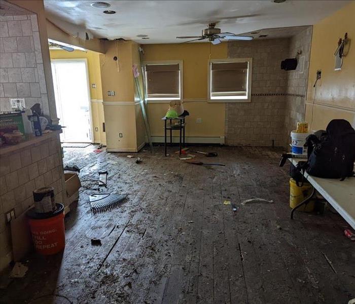 Extensive water damage and debris on living room walls, ceilings, and floors